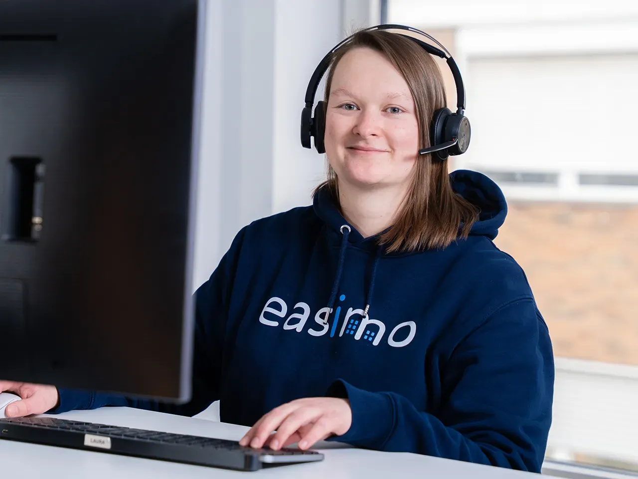 Support bei easimo: Mitarbeiterin mit Headset unterstützt Kunden bei Fragen zur webbasierten Immobilienverwaltungssoftware.